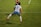 A soccer player is captured in mid-air, seemingly in the midst of a dynamic move or leap on the field. The player wears a jersey with the number 9 and the name Kawasumi on the back, along with white shorts, long white socks, and bright orange cleats. The green grass of the soccer field with white boundary lines can be seen, suggesting an active sports setting. Another player in the background is partially visible, wearing a different team’s uniform.
