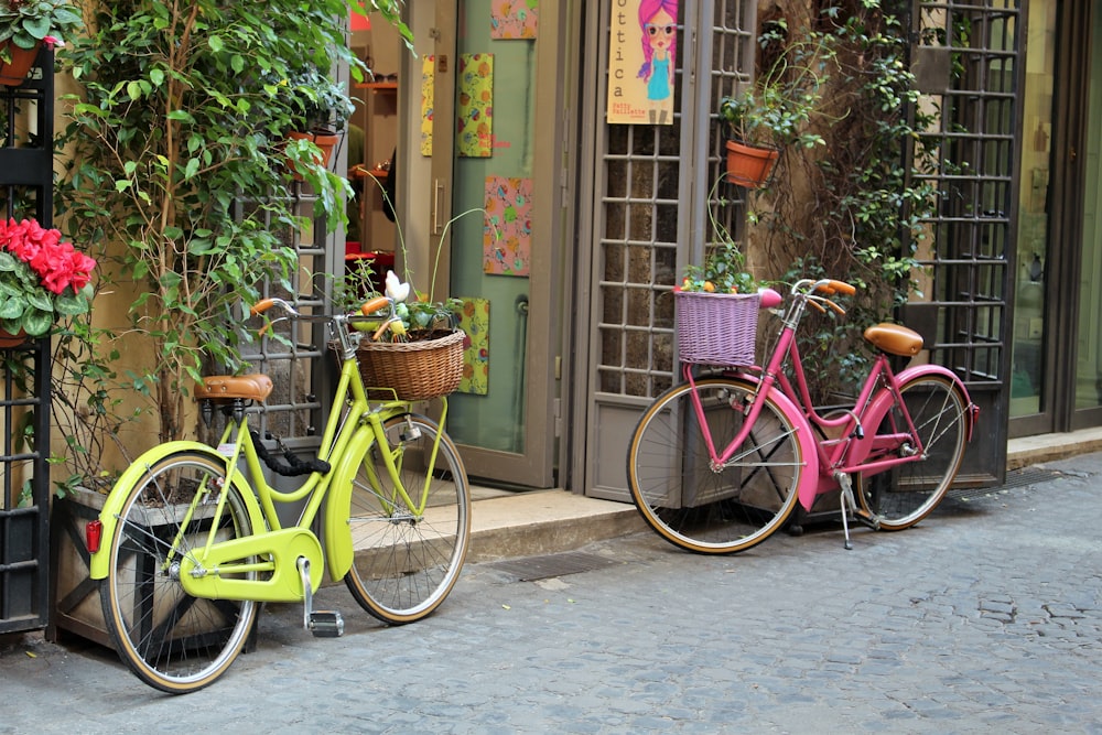 two green and pink cruiser bicycles parked by the building