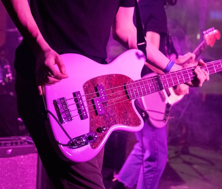 Johnny Cordon passionately playing his pink guitar on stage with the pink Cadillac backdrop shining under vibrant lights.