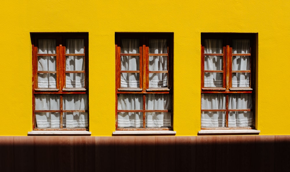 three wooden framed windows and white curtains