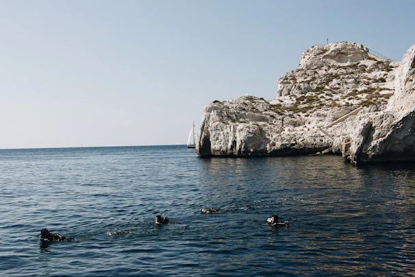 A small group of divers swimming side by side over a stunning underwater wall.