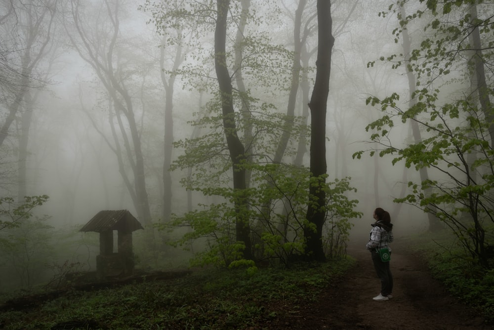 woman in white jacket standing in the forest