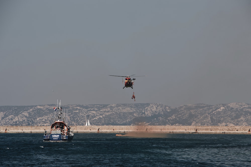 red helicopter flying above sea