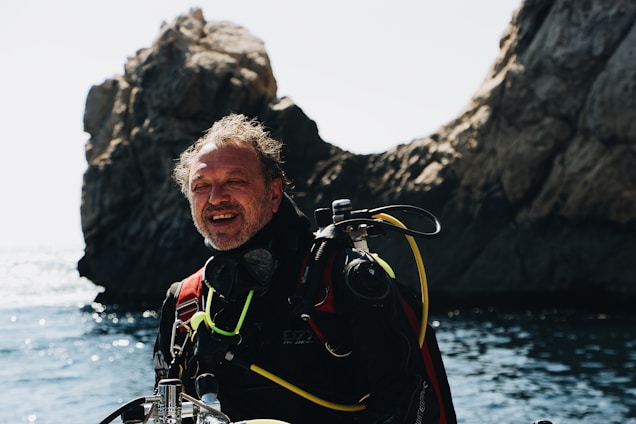 A smiling scuba instructor in deep ocean blue wetsuit with a happy dog mascot on the sunny shores of Tenerife.