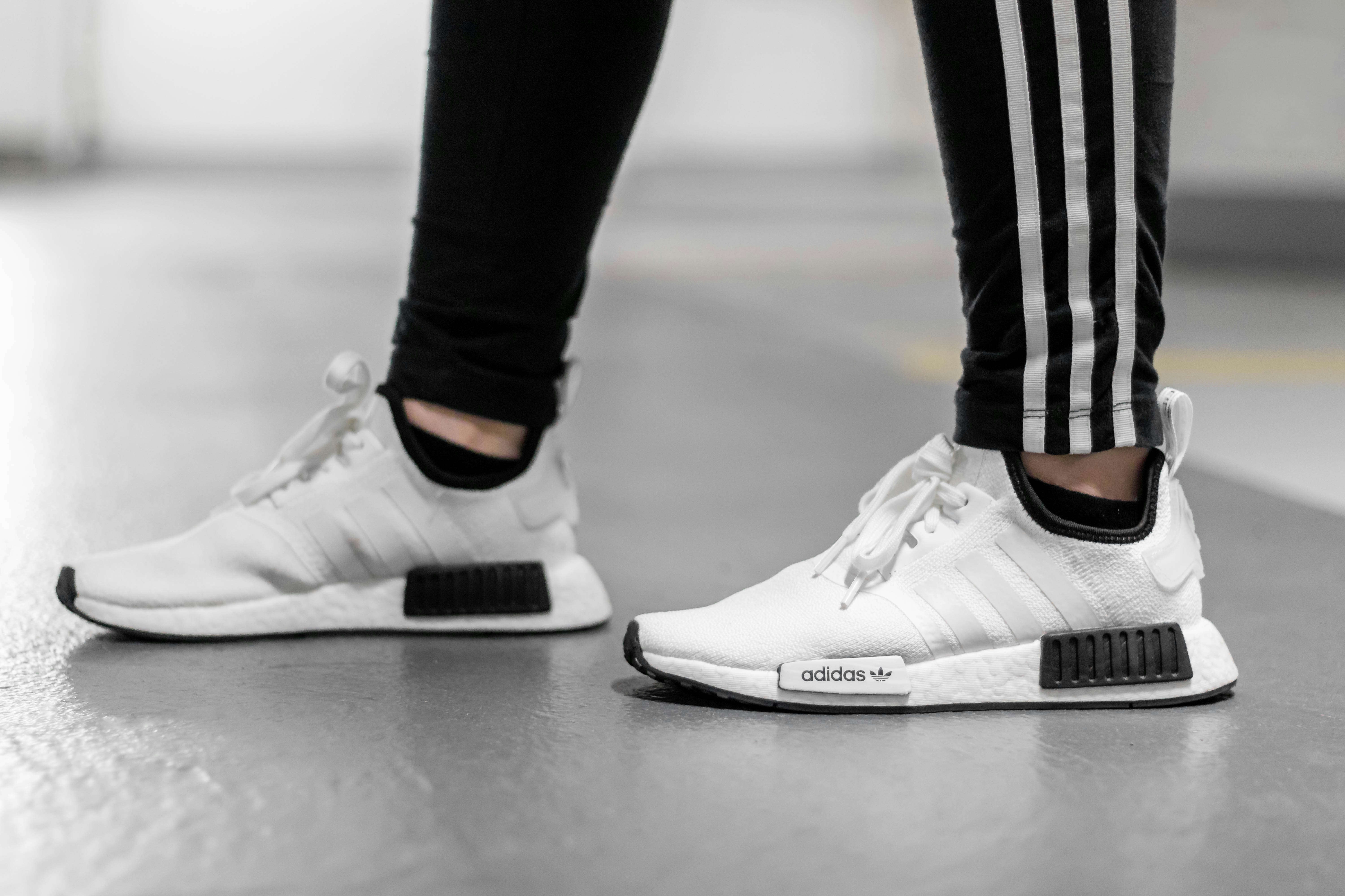 person wearing white Adidas NMD shoes