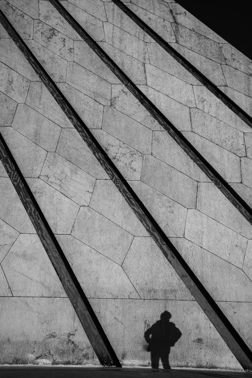 una foto in bianco e nero di una persona in piedi di fronte a un muro