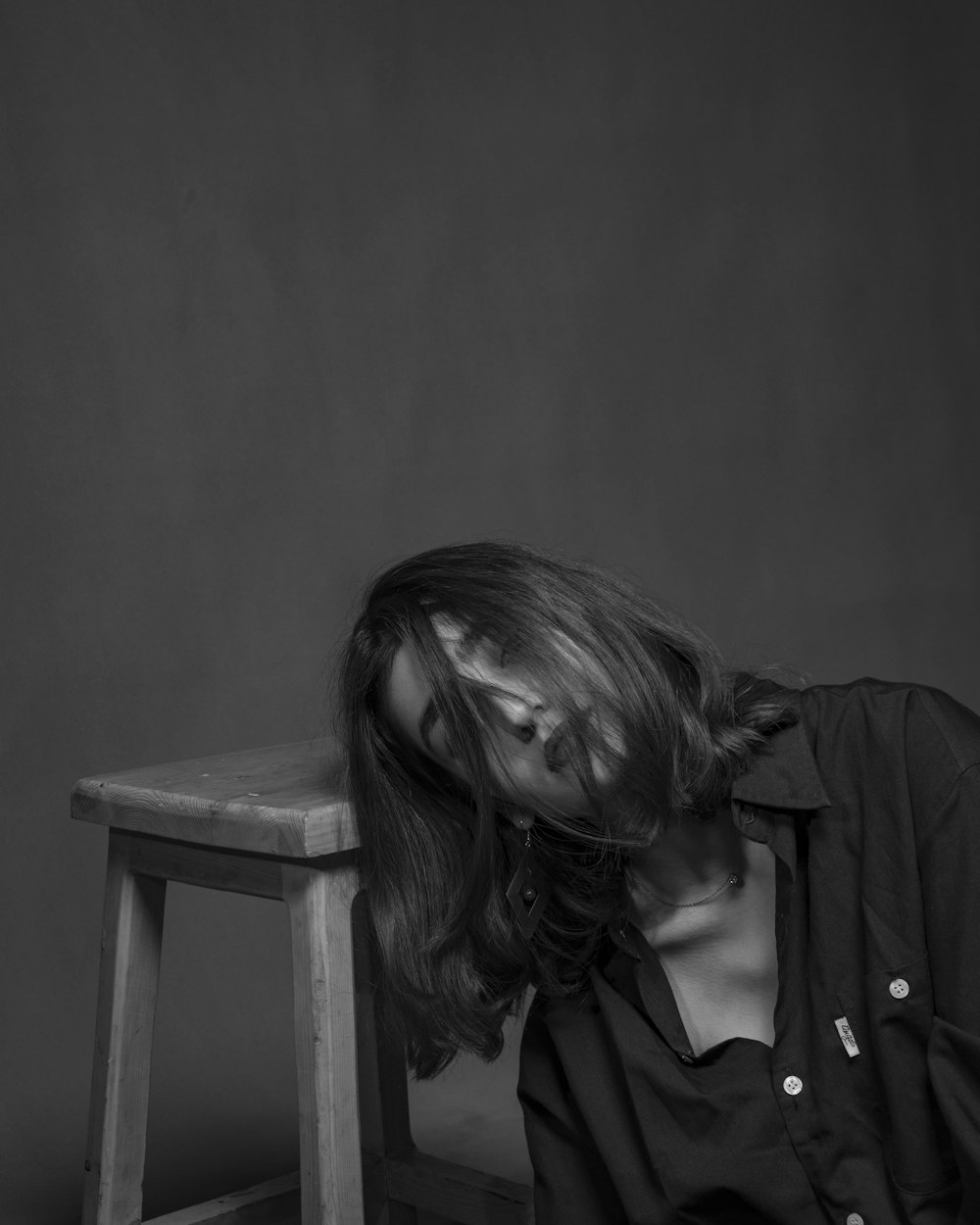 grayscale photo of woman sitting beside chair
