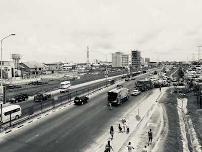 A busy street with cars cautiously driving around scattered potholes.