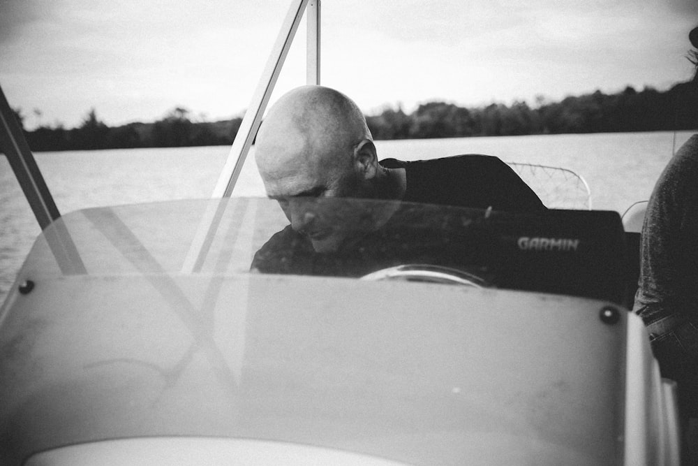 grayscale of man riding on boat