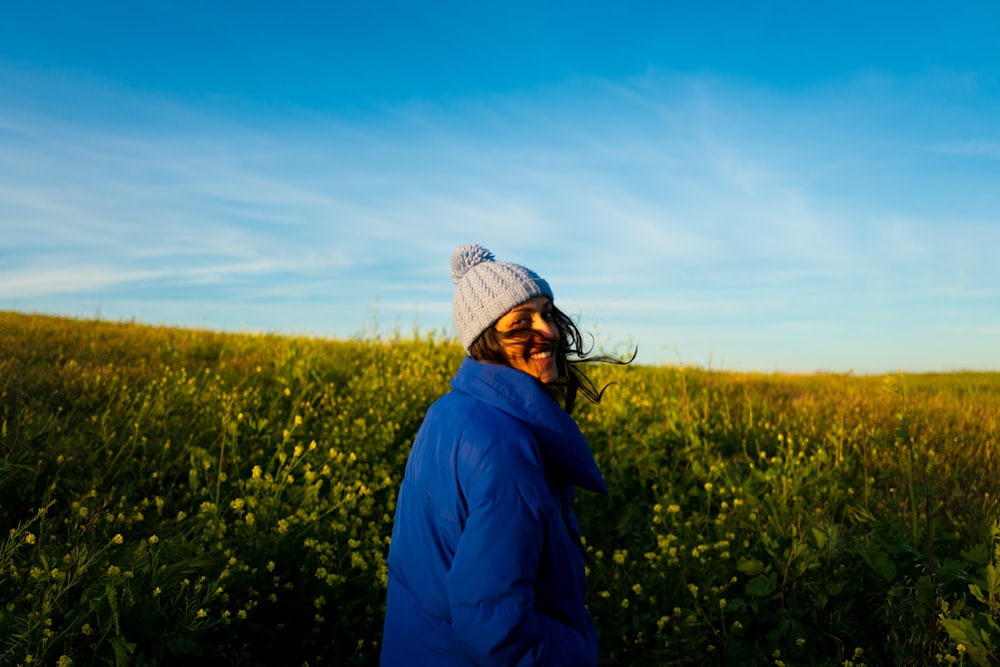 woman wearing blue jacket and ball knit cap standing on field