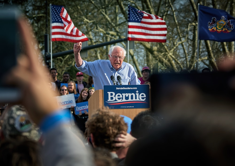 man standing on lectern surrounded by people