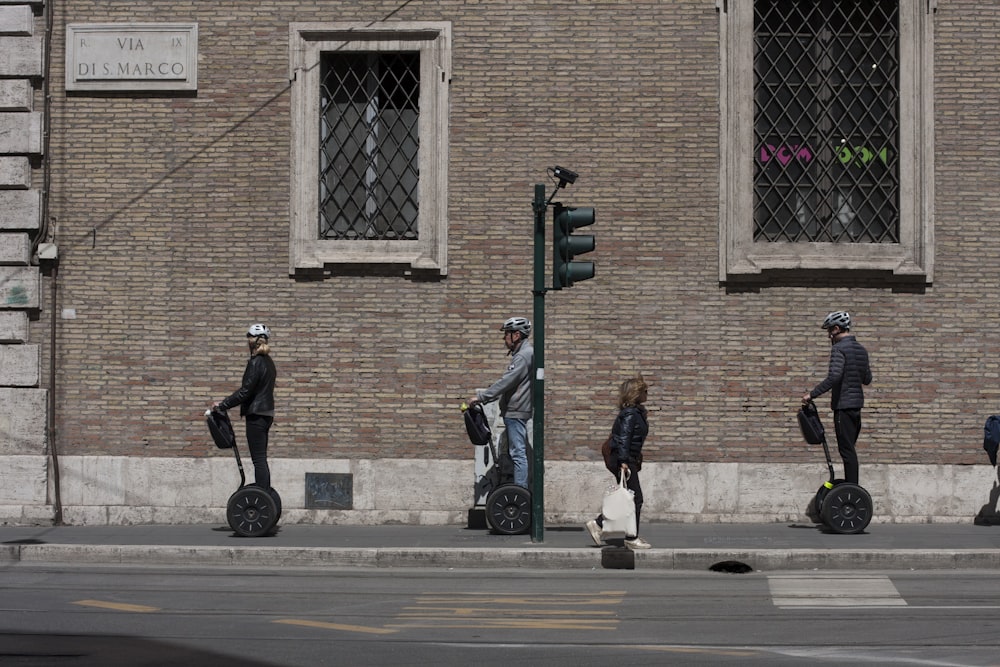 three people riding on black footsegway