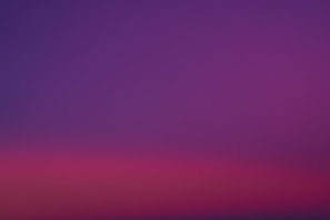 a purple and pink sky with a plane in the distance