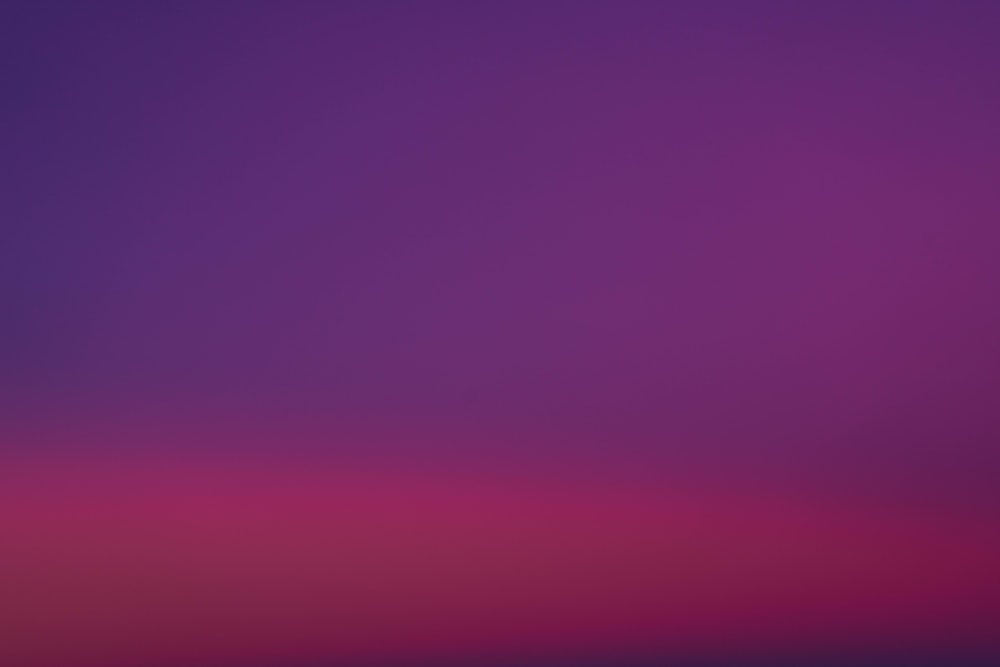 Un cielo viola e rosa con un aereo in lontananza