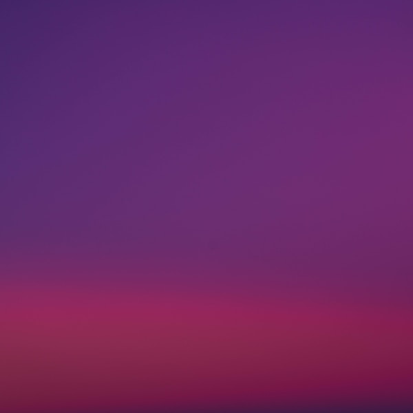 a purple and pink sky with a plane in the distance