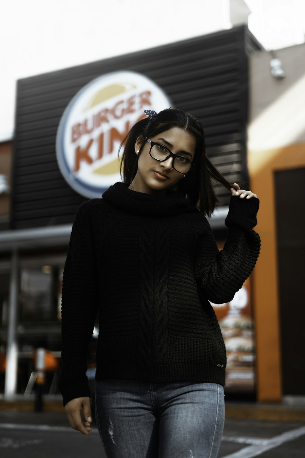 mulher vestindo suéter de malha preto ao lado do Burger King