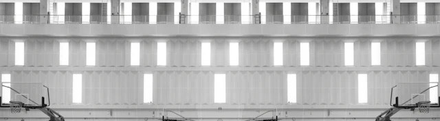 Modern indoor gymnasium with polished wooden floor, basketball hoops, and bright overhead lighting