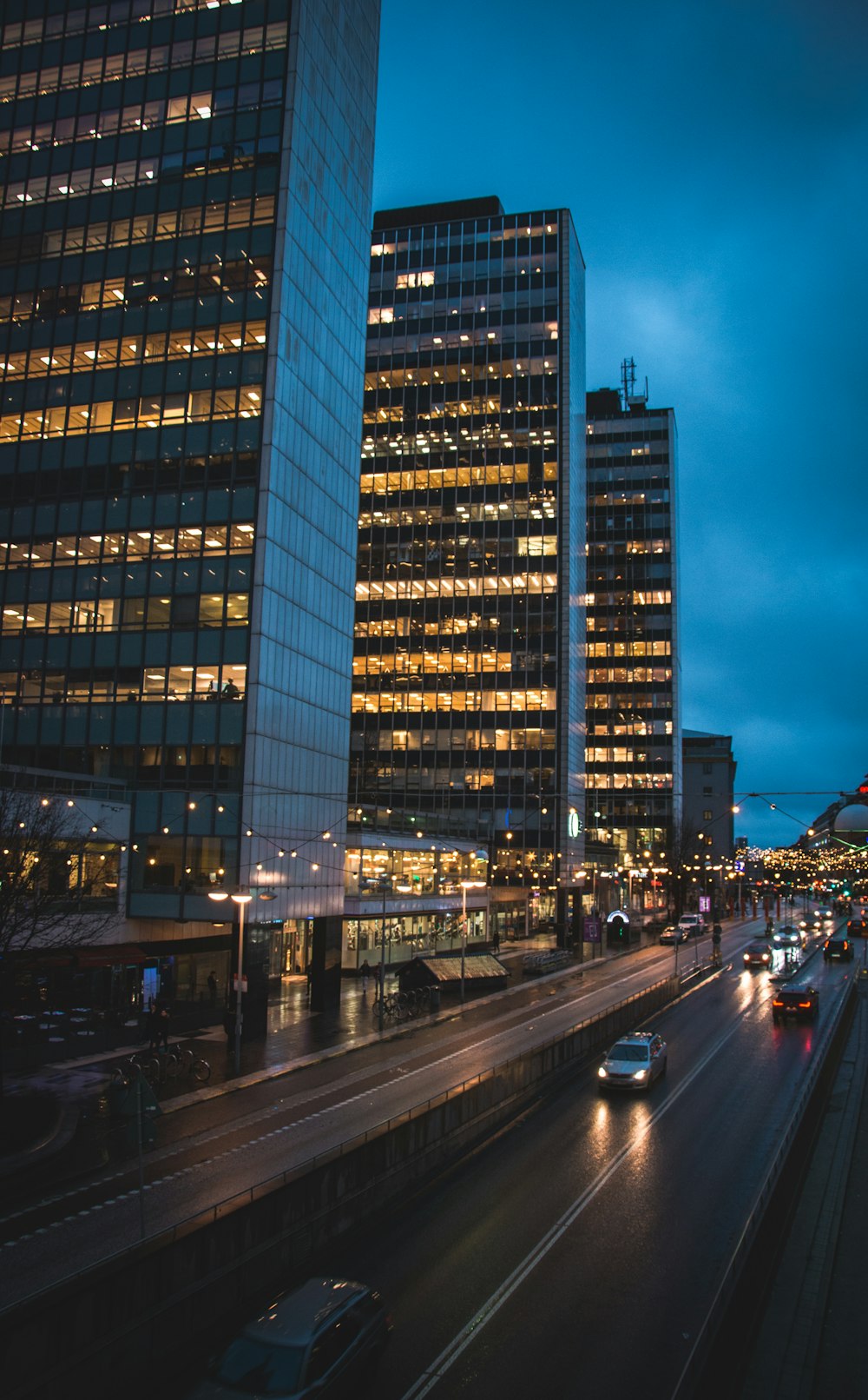 vehicles running beside high rise buildings at night