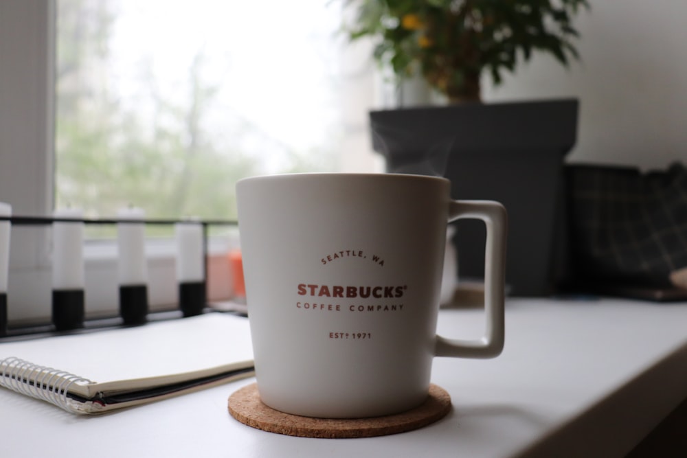 white Starbucks sceramic mug on coaster on table