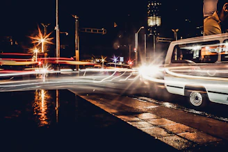 A nighttime cityscape with a transport van driving through illuminated streets.