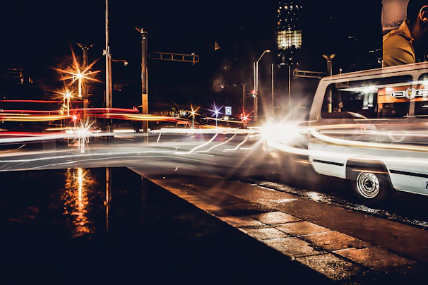 A nighttime cityscape with a transport van driving through illuminated streets.