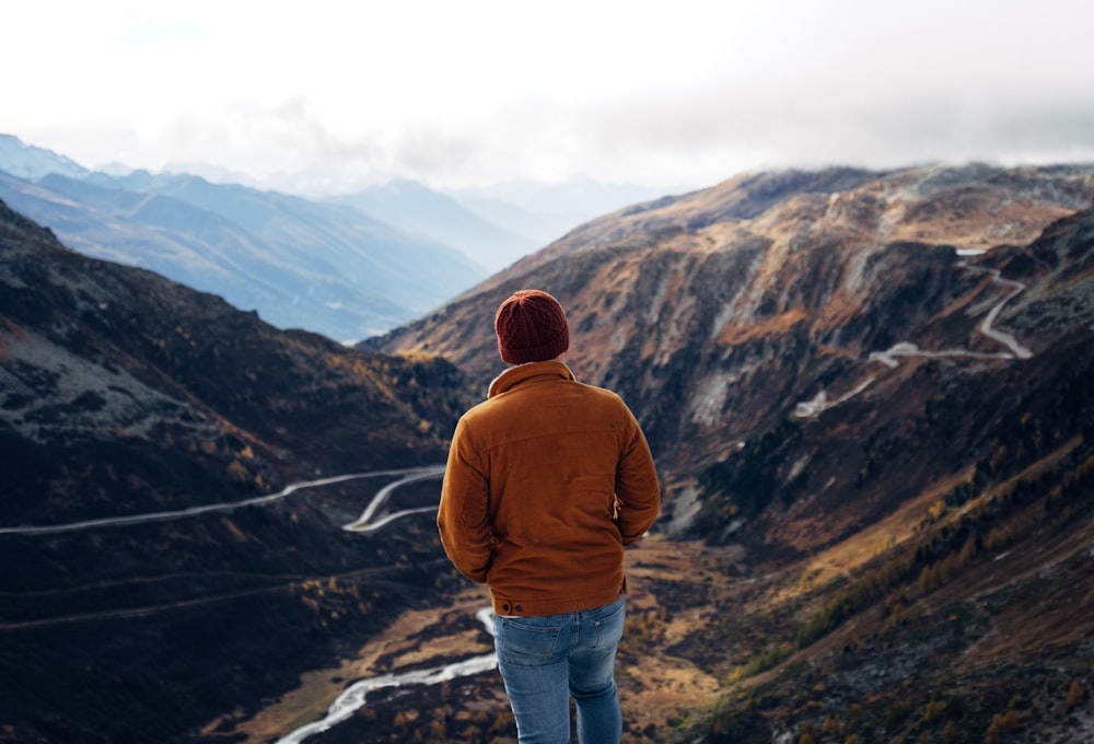 person wearing brown knit cap standing on brown mountain