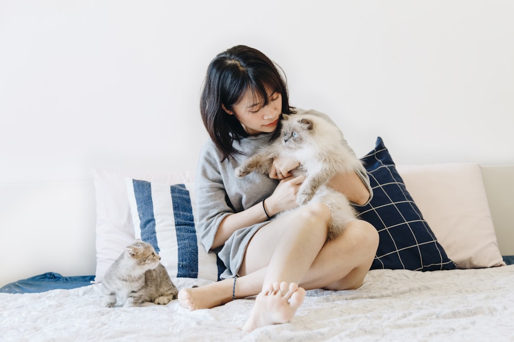 Mujer sosteniendo gato al lado de otro gato