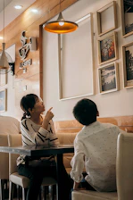 A warm, inviting scene of two friends laughing together at a cozy café with soft pink accents.