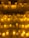 Numerous lit candles of varying heights are organized on several shelves, with wax dripping down the sides, creating an ambient and warm glow.