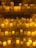 Numerous lit candles of varying heights are organized on several shelves, with wax dripping down the sides, creating an ambient and warm glow.