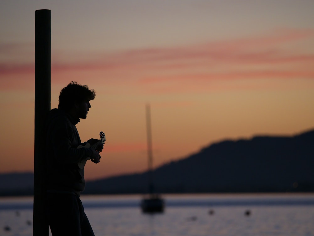 a man standing next to a pole near a body of water