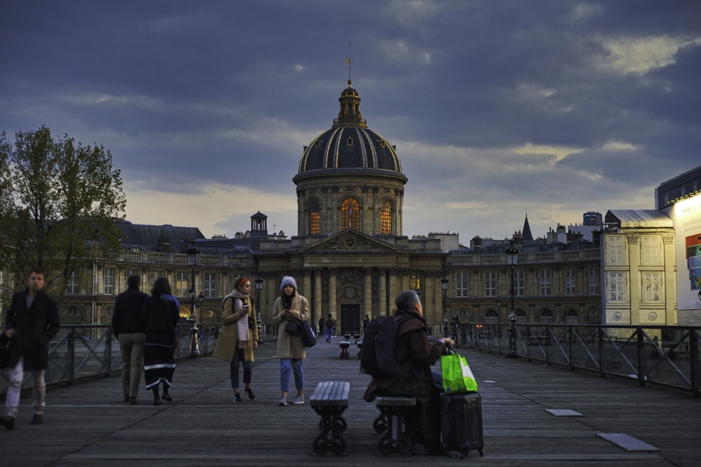 people walking and sitting in front of brown concrete dome building during golden hour