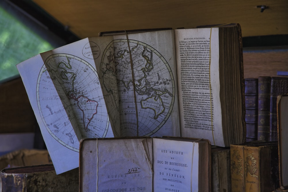 a stack of old books with maps on them