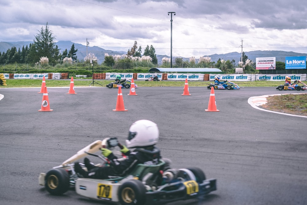 man riding go-kart near traffic cones during daytime