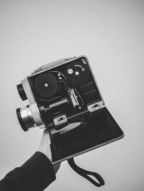 Close-up of a robotic hand holding a vintage film camera, blending old and new media.