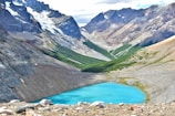 Moraine Lake’s vibrant blue waters framed by rugged peaks and pine trees in early morning light.