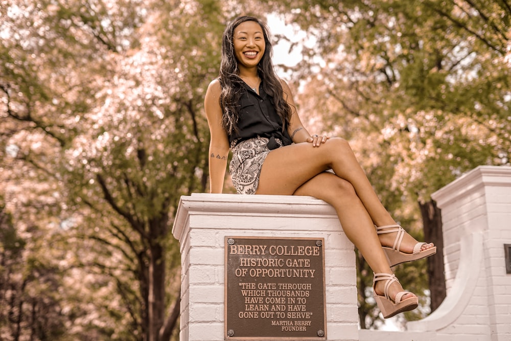 smiling woman sitting on concrete fence