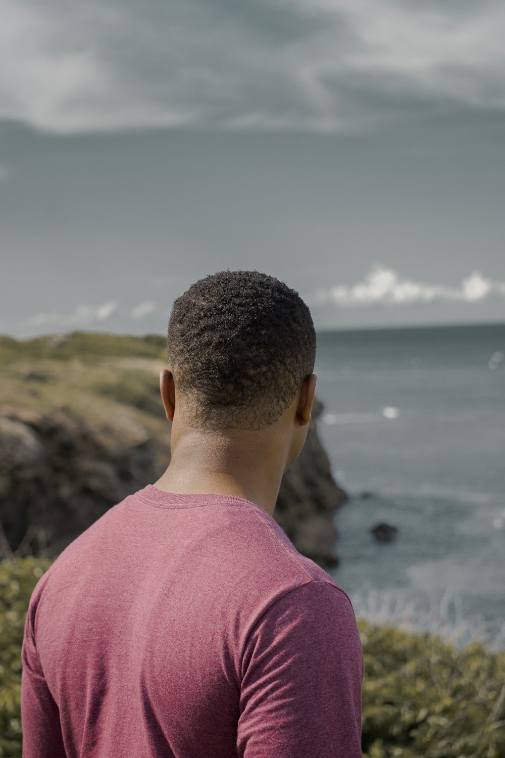 man wearing pink crew-neck shirt on mountain cliff during daytime