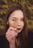 A close-up of a woman wearing earth-toned makeup surrounded by autumn leaves.