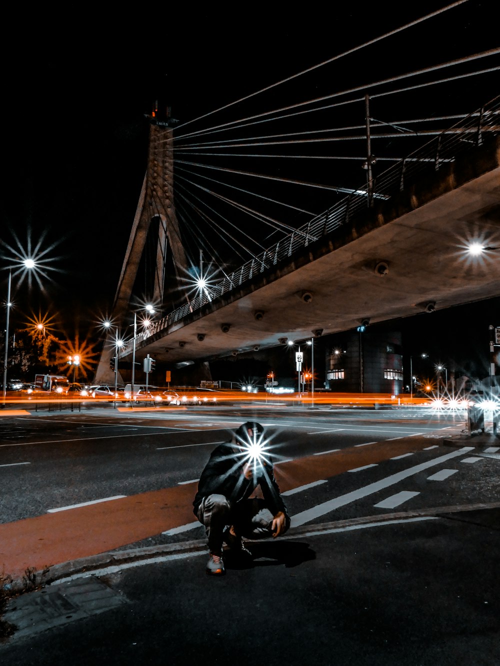 man squatting on pathway during night