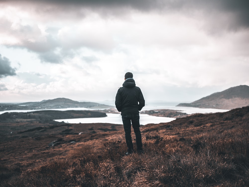 person standing on high ground near lake\