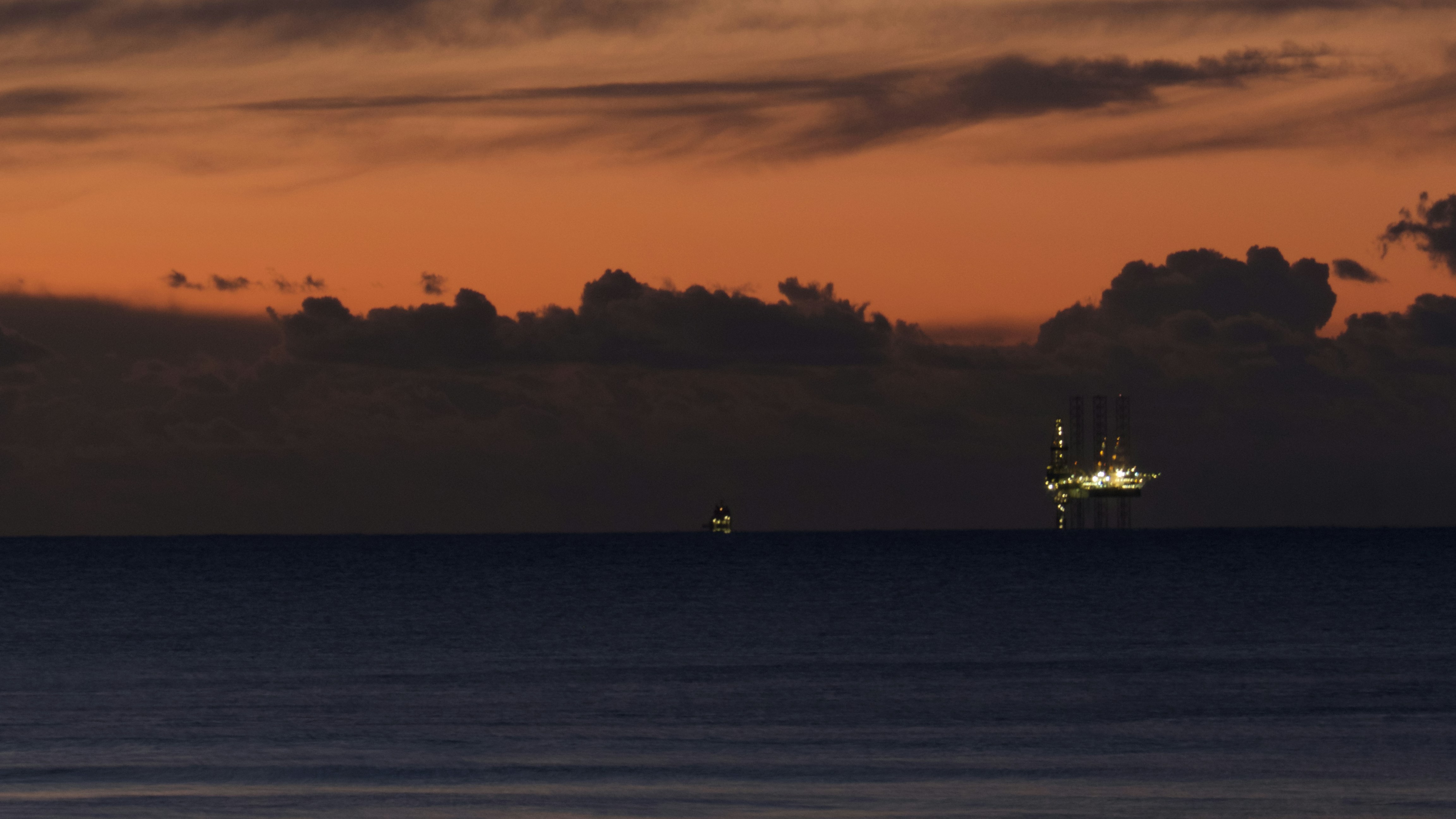 Offshore oil platform in open sea at dusk, dark ocean, industrial lighting