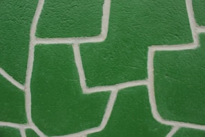 Green, textured wall pattern consisting of irregular geometric shapes separated by white grout lines.