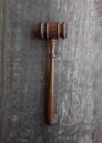 A close-up of a vintage law book with a gavel resting on top, set against a dark wooden background.