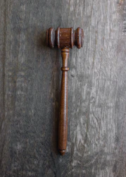 Gavel resting on legal documents with a warm wooden desk background.