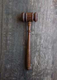 Close-up of legal documents and a gavel resting on a polished wooden desk.