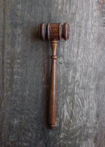 Law books and a gavel resting on a polished dark wood table.