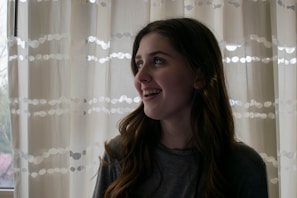 Smiling woman looking out a window, embodying hope and empowerment.