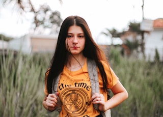 woman wearing orange crew-neck T-shirt with backpack