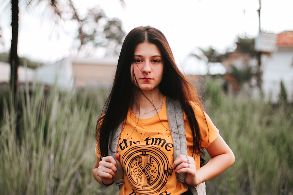 woman wearing orange crew-neck T-shirt with backpack